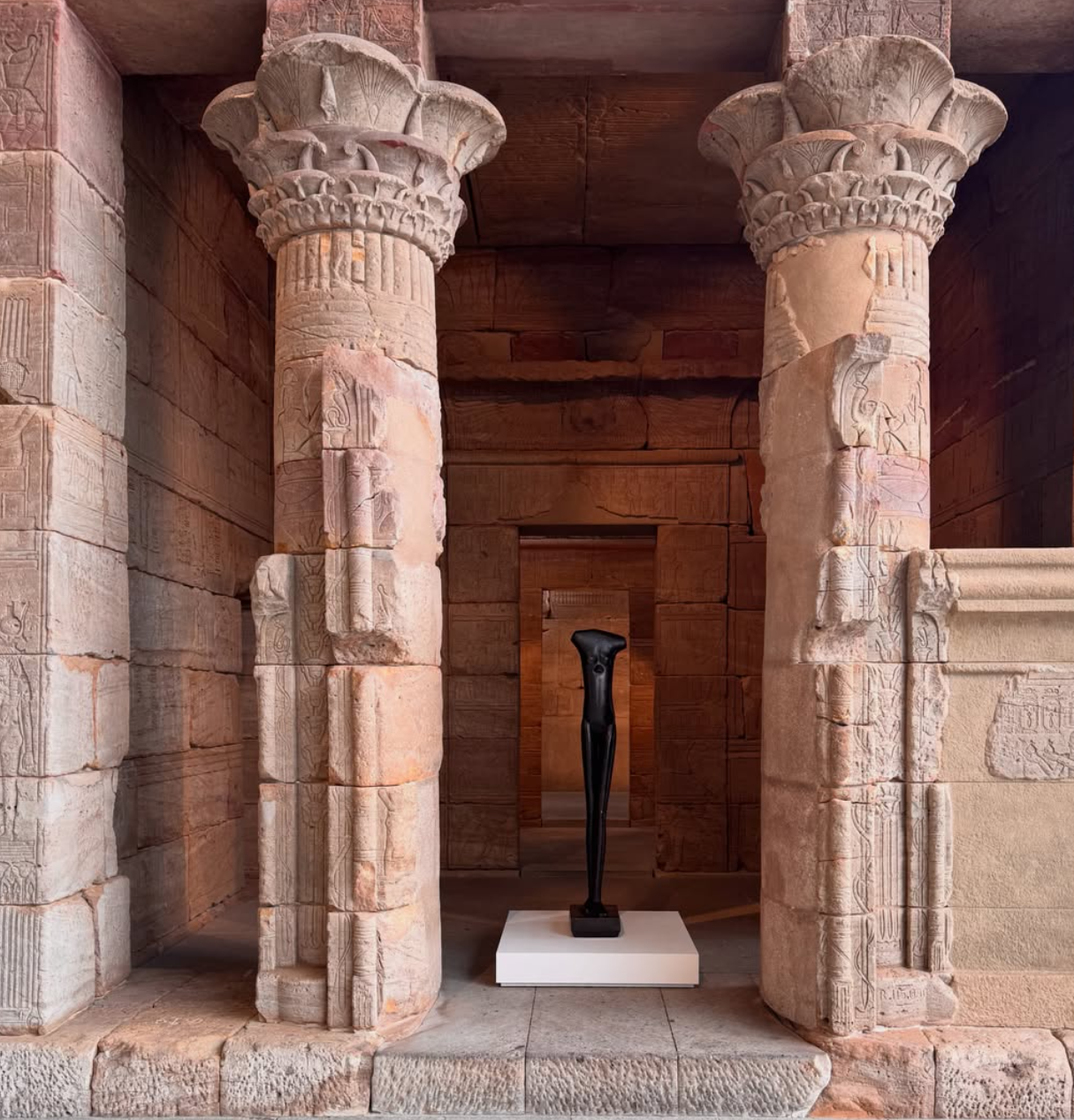 Alberto Giacometti, Walking Woman, a slender black bronze figure standing on a white plinth inside the Temple of Dendur, the Metropolitan Museum of Art