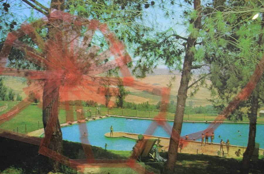 Tanja Lazetic work: a 1970s Israeli postcard of a kibbutz swimming pool full of bathers, seen through green pine trees, overlaid with broken glass held together by translucent red tape in a spoked wheel pattern