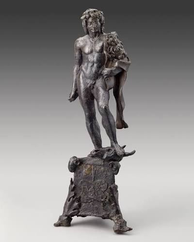 Dark bronze statuette of a standing nude male figure with a lion skin over his arm, standing on a small decorated base