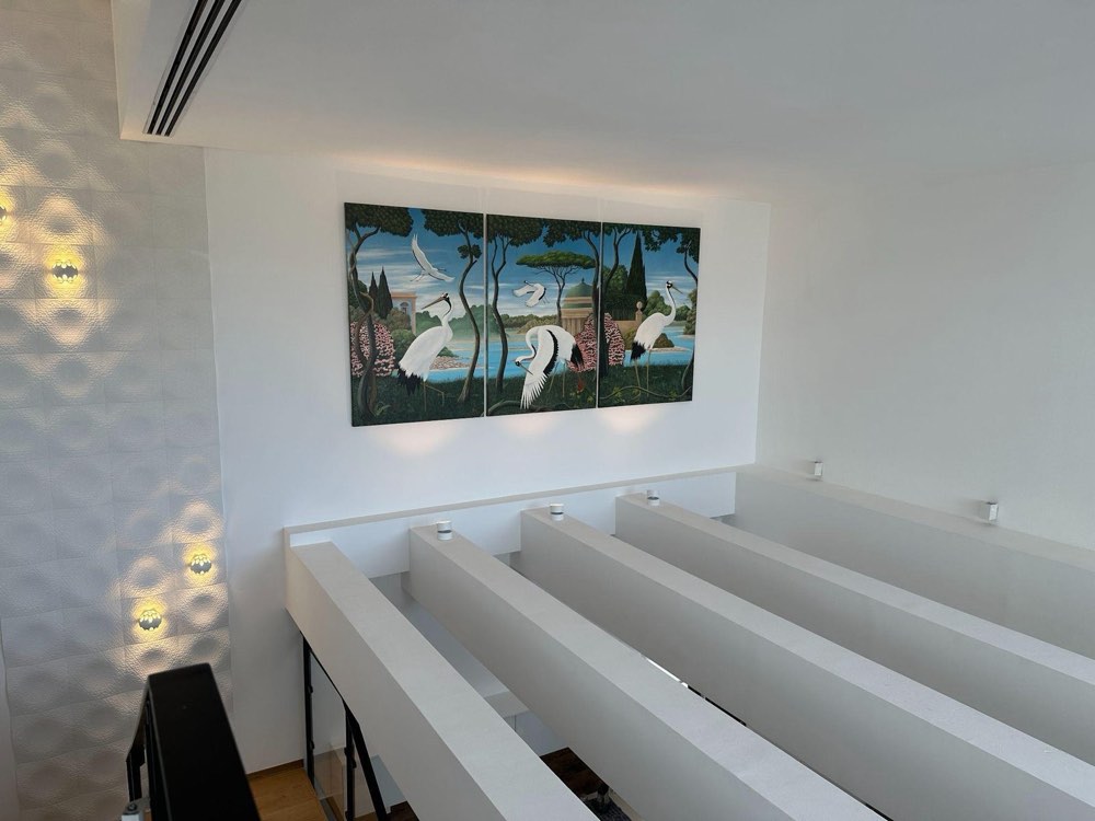 The three panel stork triptych installed on a white wall