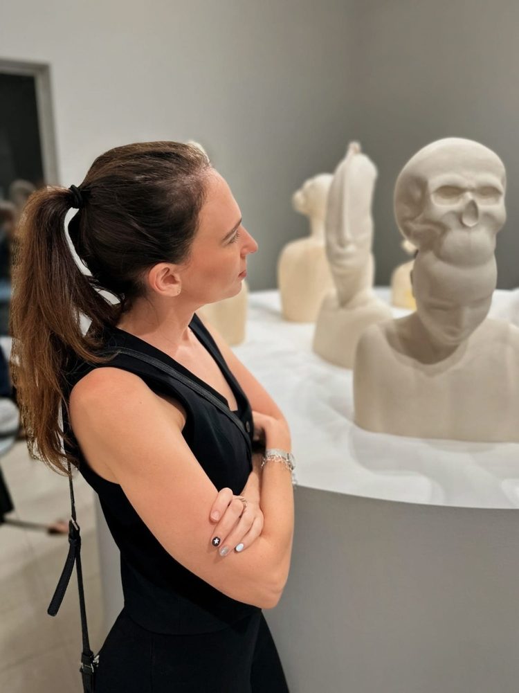 Stav Theodor in black, studying white sculpted busts on a gallery plinth