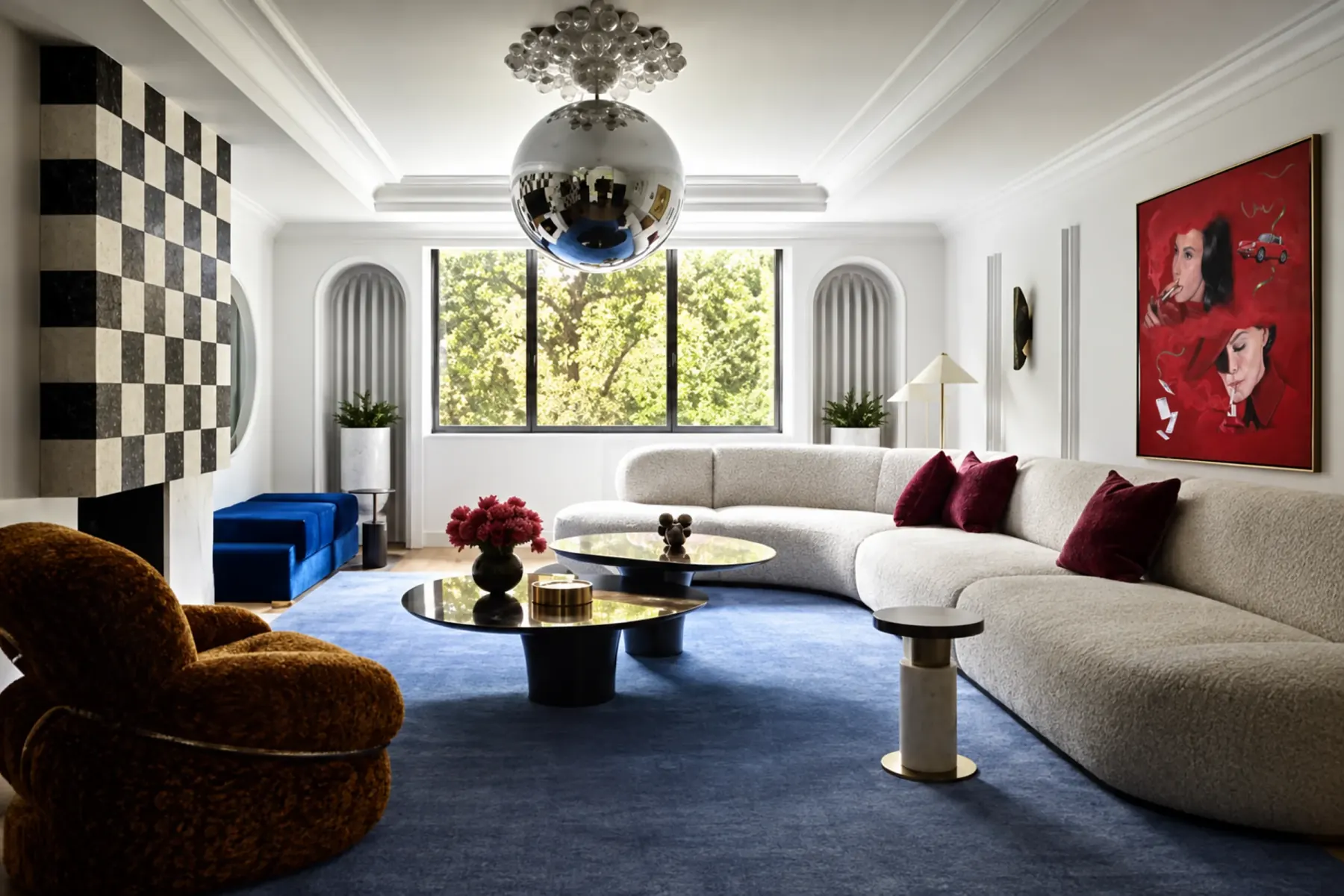 A living room with a blue carpet, a curved sofa and a red portrait on the right wall.