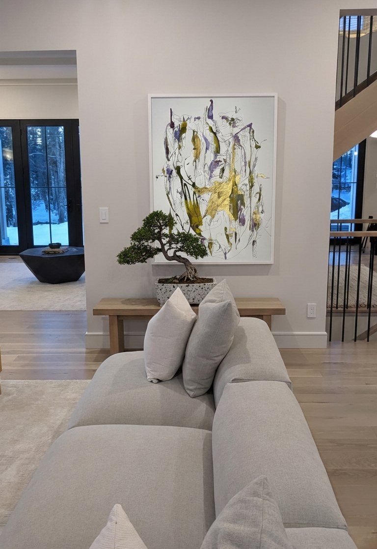 Hall in Closter, New Jersey, a large abstract work in gold, olive and violet in a white frame above a wood bench with a bonsai, beside the stair