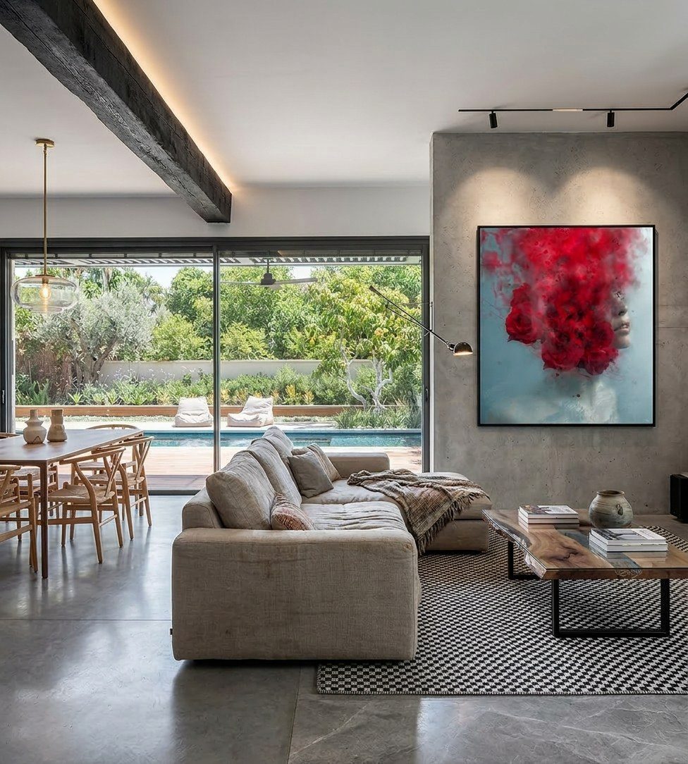 Living room in Hod Hasharon with a large figurative artwork in red on a concrete wall, garden and pool beyond the glass